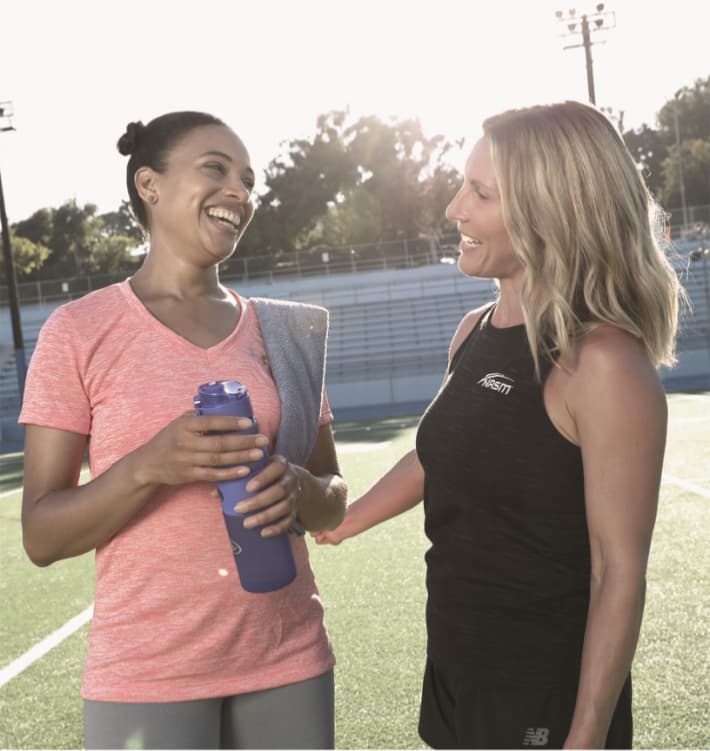 Image of two women chatting on a football field