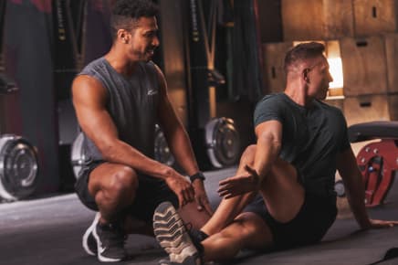 A male trainer helps a client stretch