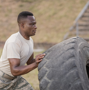 A male soldier flipping a tire
