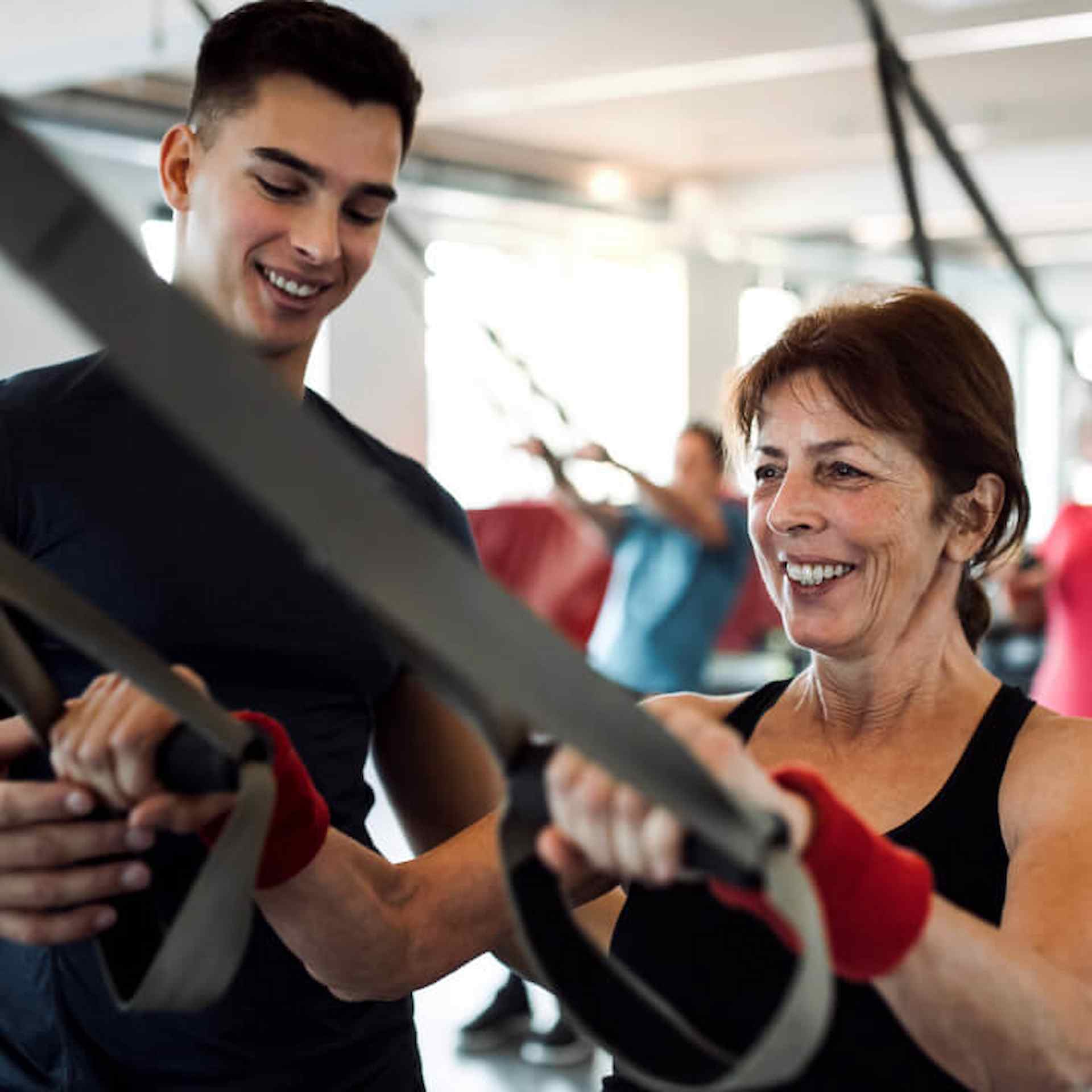 A elderly woman working out next to a male trainer