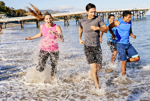 A group of men and women running in the ocean