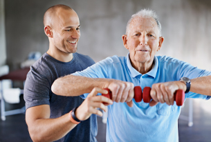 A younger man helping a senior work out