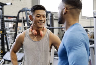 A Personal Trainer advises a client in a weight room