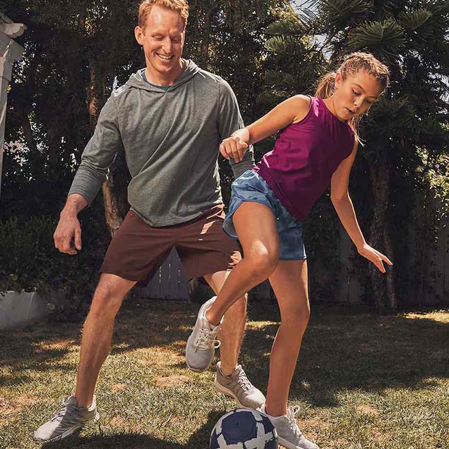 Father and daughter playing soccer in their backyard