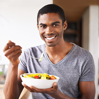 Male smiling at camera holding bowl of fruit