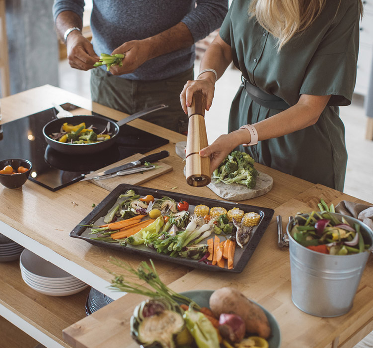 two people cooking vegetables in kitchen
