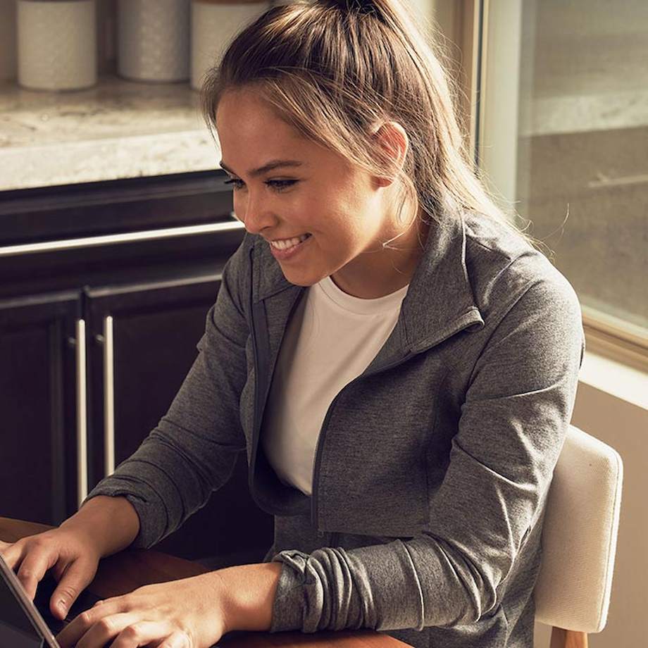 Female sitting in kitchen typing on laptop
