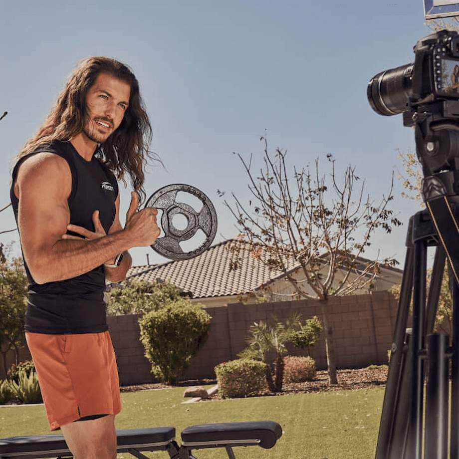 Male NASM coach filming an arm workout with small weighted plate