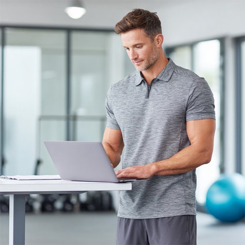 Man standing typing on a laptop