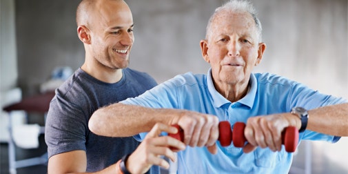 A male trainer helping a senior client