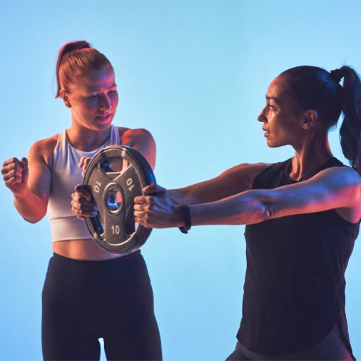 woman holding a weight plate woman coaching her