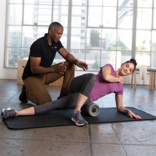 Man helping a woman stretch with foam roller