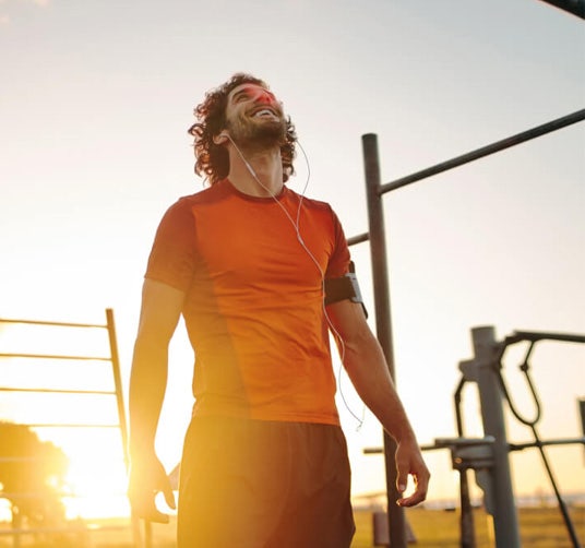 A man in fitness gear listens to music at sunrise