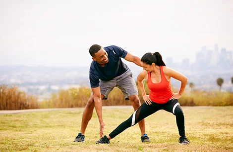 trainer outdoors stretching with client