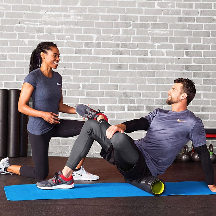 A trainer teaches a man to foam roll